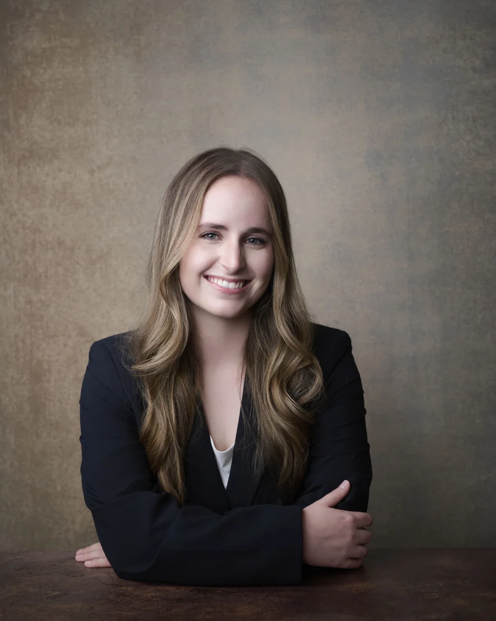 Ashton Steed, actor headshot with bright smile in black blazer against warm painted backdrop by Marie Feutrier