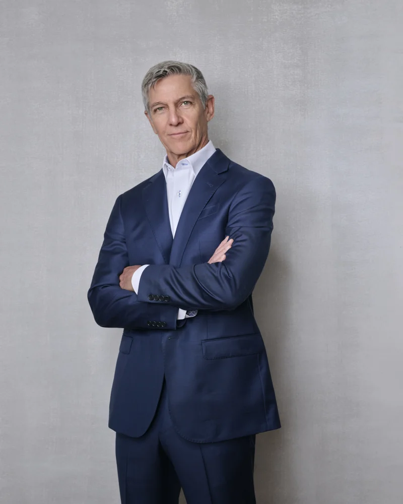Executive in a navy suit and white dress shirt with arms crossed for a professional business portrait