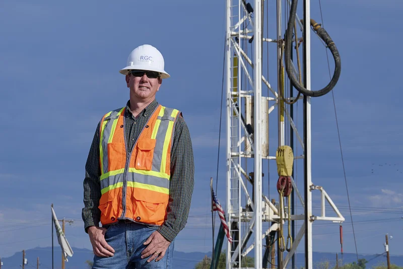 Construction professional wearing a hard hat and orange safety vest standing at a job site for a business portrait