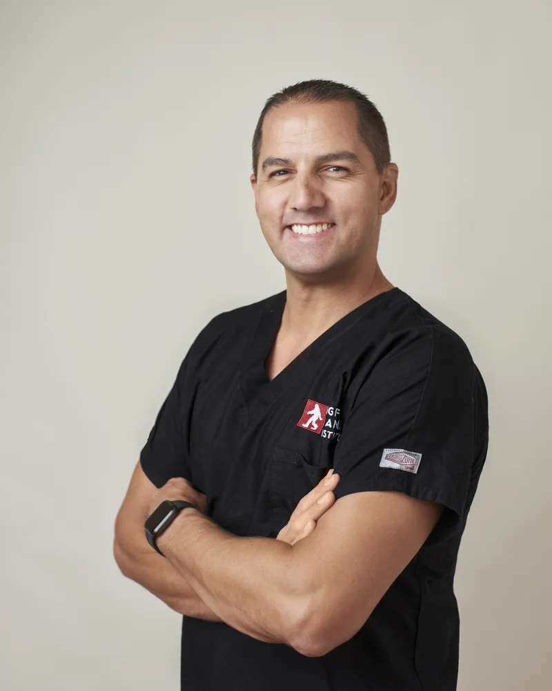 Healthcare professional in black medical scrubs with arms crossed smiling for a headshot
