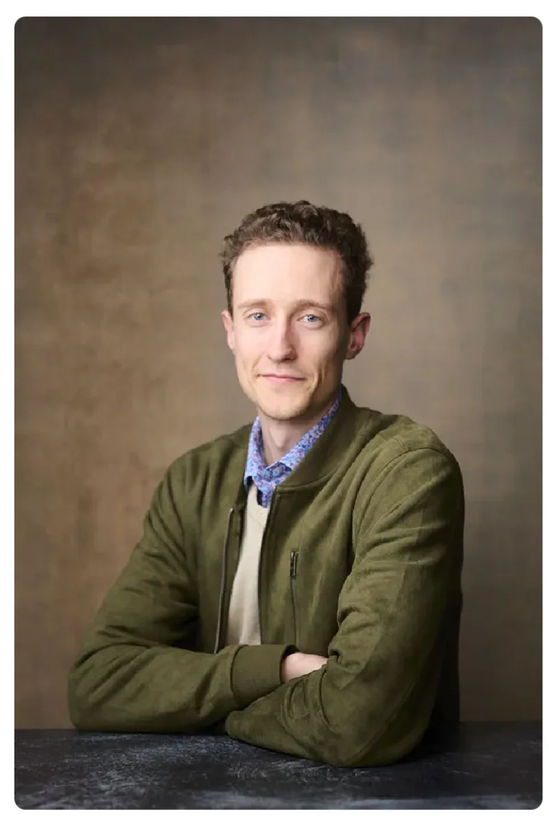 Author and speaker holding his book and iced coffee in a white button-down shirt against a bold yellow background for a personal branding portrait