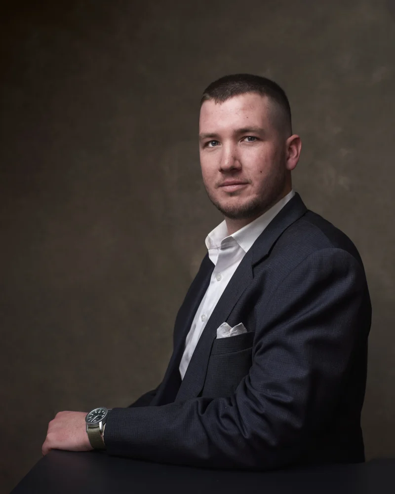 Man in a dark suit with a white pocket square and watch showing how subtle accessories elevate a professional headshot