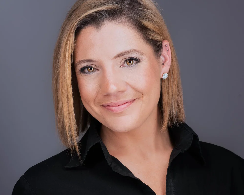Gina with honey-blonde bob in black button-down shirt warm smile employee headshot against gray backdrop Phoenix Arizona