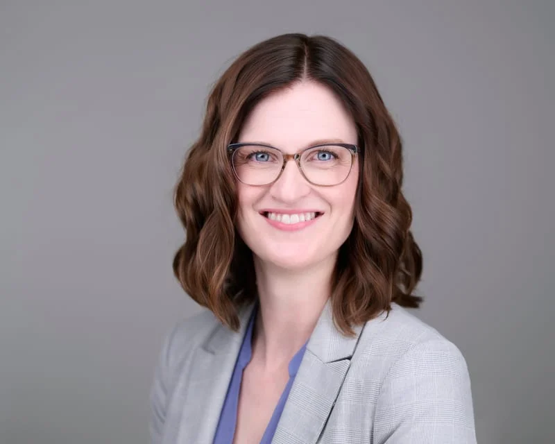 ERAS headshot of female medical student in gray blazer with glasses formatted for residency application