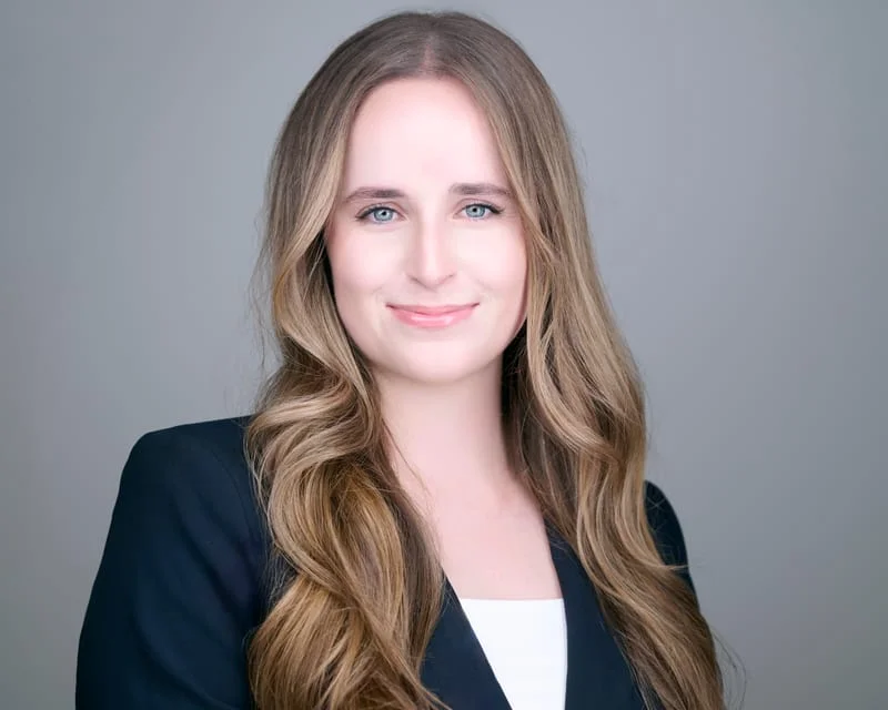 Woman with long blonde hair in black blazer over white top friendly smile ERAS headshot against gray backdrop Phoenix