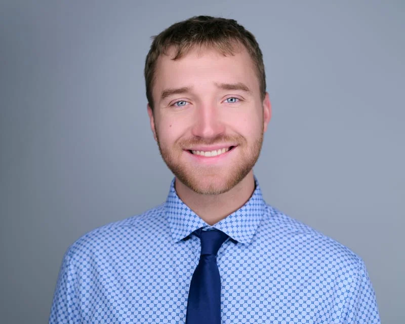 Friendly professional headshot for medical residency application of male student in blue dress shirt and tie
