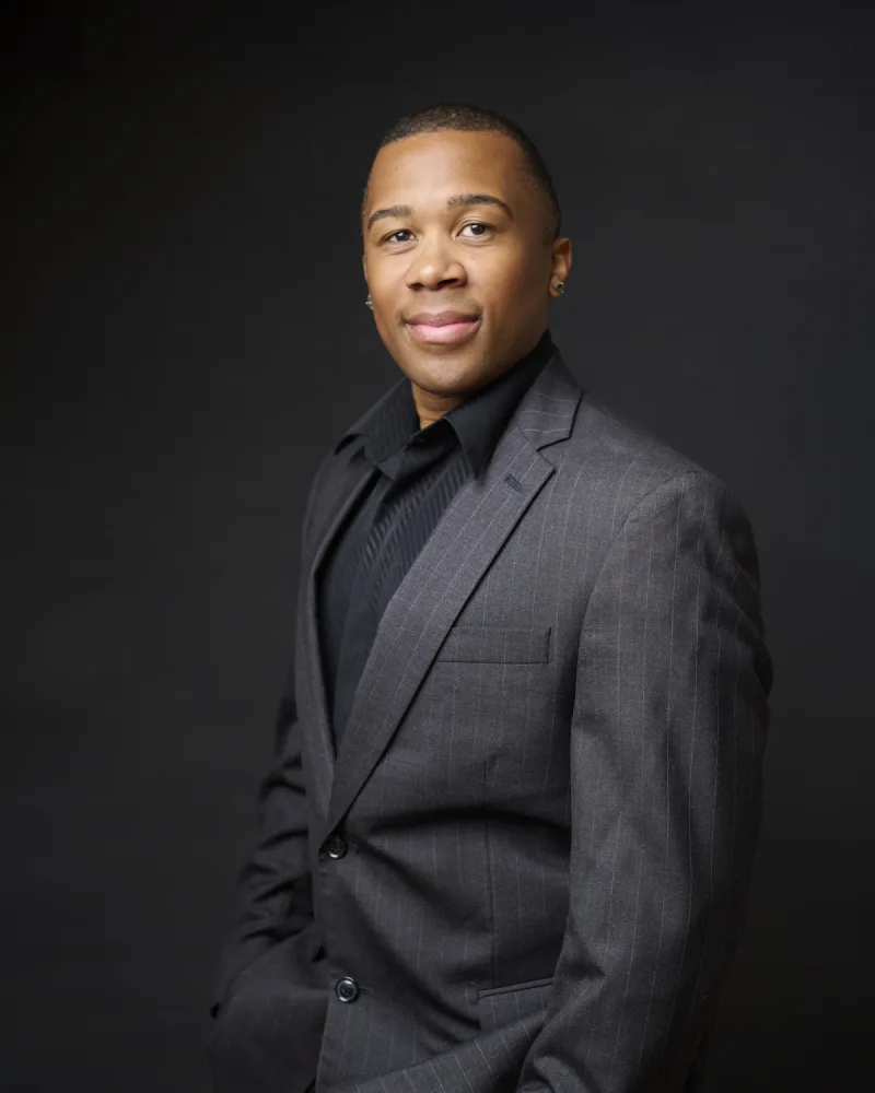 LJ Walker executive headshot in gray pinstripe suit against dark backdrop Phoenix Arizona